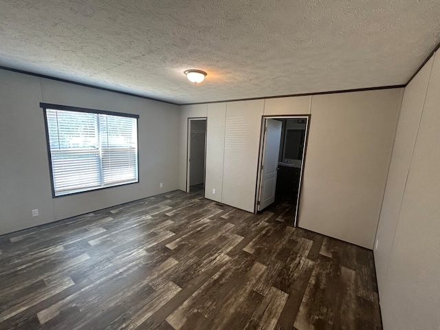 unfurnished bedroom with dark wood-type flooring, connected bathroom, and a textured ceiling