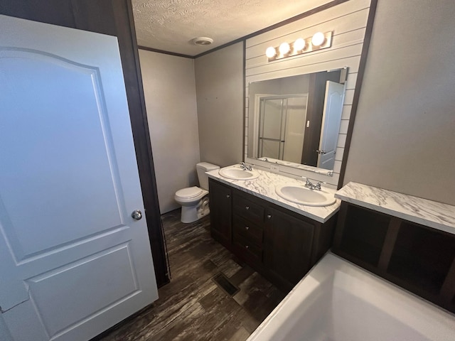 full bathroom featuring a textured ceiling, vanity, separate shower and tub, wood-type flooring, and toilet