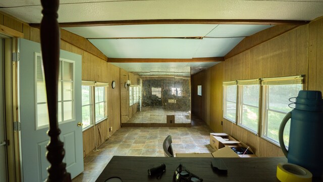 workout area with vaulted ceiling, a textured ceiling, and wood walls