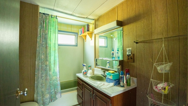 full bathroom featuring wood walls, shower / bath combination with curtain, toilet, and vanity