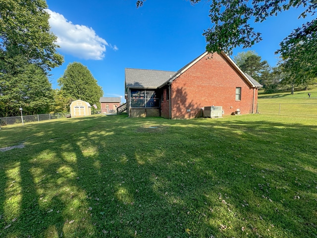 view of side of home with a yard, cooling unit, and a shed