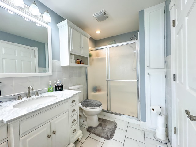 bathroom with toilet, a shower with door, vanity, decorative backsplash, and tile walls