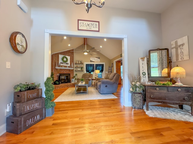 living room with hardwood / wood-style flooring, high vaulted ceiling, a brick fireplace, and ceiling fan