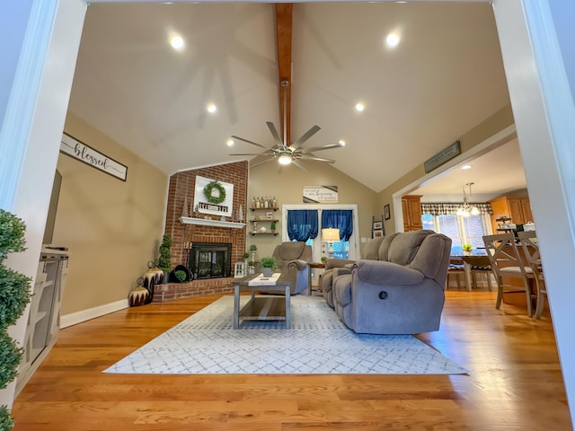 living room featuring light hardwood / wood-style floors, ceiling fan with notable chandelier, beam ceiling, and a fireplace