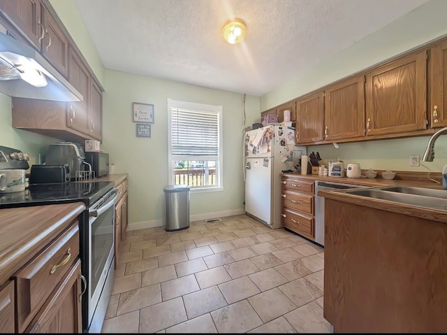 kitchen featuring white refrigerator, a textured ceiling, light tile patterned floors, and electric range