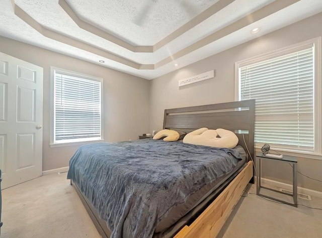 carpeted bedroom featuring a textured ceiling and a raised ceiling