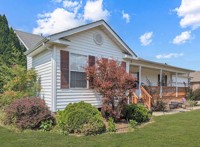 rear view of property featuring a lawn and a porch