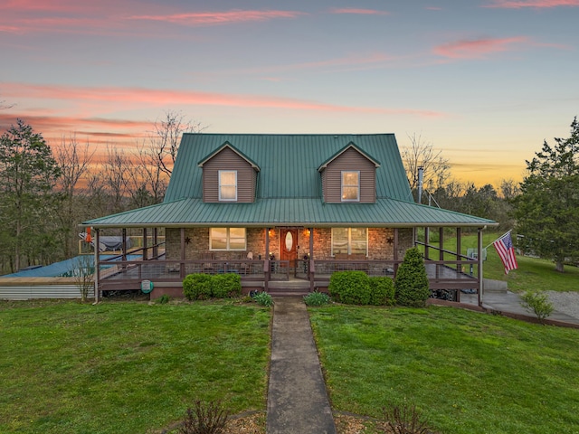 farmhouse with covered porch, stone siding, metal roof, and a yard