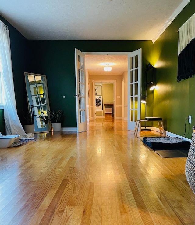 interior space with ornamental molding, french doors, a textured ceiling, and light hardwood / wood-style floors