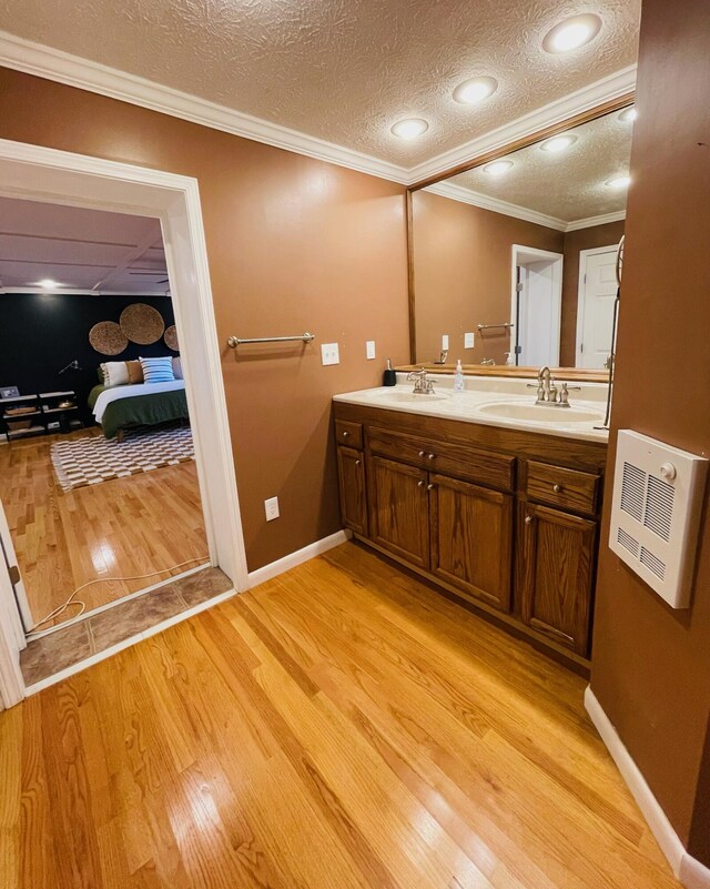 bathroom featuring hardwood / wood-style floors, crown molding, vanity, a textured ceiling, and heating unit