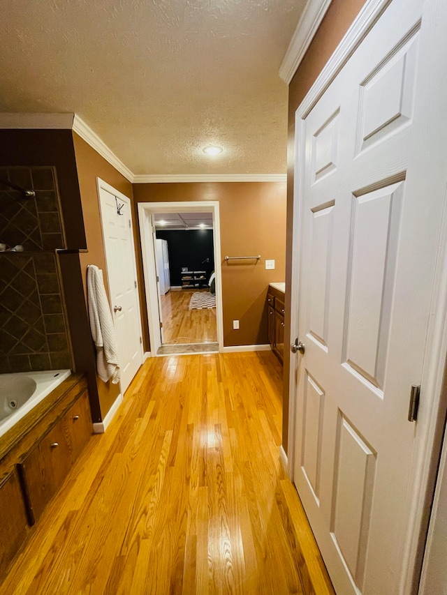 hall featuring a textured ceiling, light hardwood / wood-style flooring, and ornamental molding