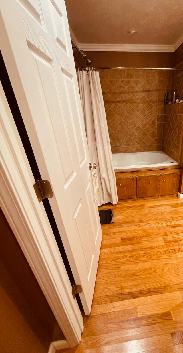 bathroom with crown molding, hardwood / wood-style floors, and shower / bath combo with shower curtain