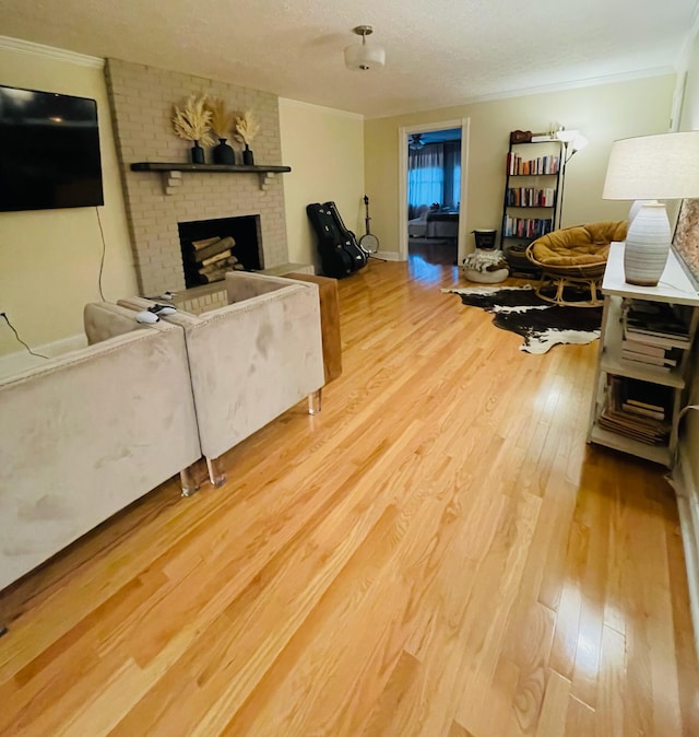 living room featuring a textured ceiling, light hardwood / wood-style flooring, crown molding, and a fireplace