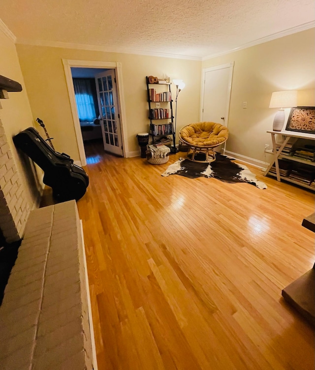 interior space featuring a textured ceiling, crown molding, a brick fireplace, and hardwood / wood-style flooring