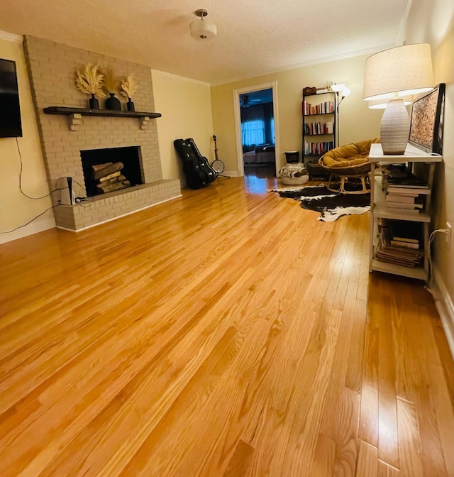 living room featuring a textured ceiling, crown molding, a brick fireplace, and hardwood / wood-style flooring