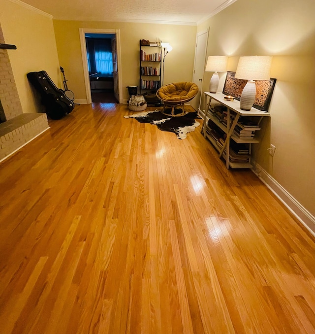 living area with ornamental molding, a brick fireplace, and light hardwood / wood-style floors