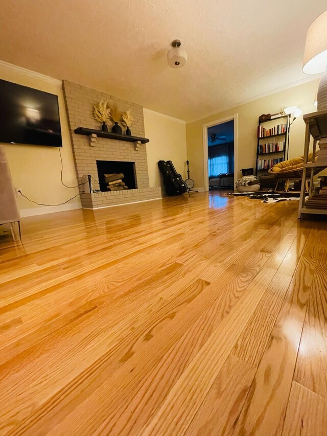 living room featuring a textured ceiling, crown molding, hardwood / wood-style floors, and a fireplace