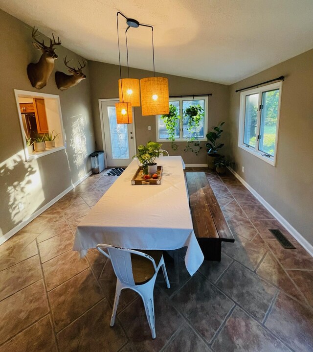 tiled dining space featuring vaulted ceiling