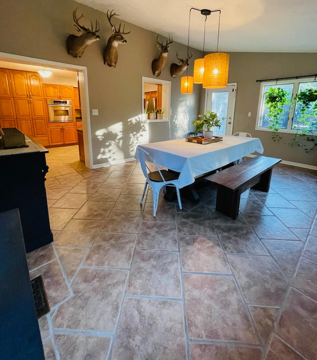 tiled dining room featuring vaulted ceiling