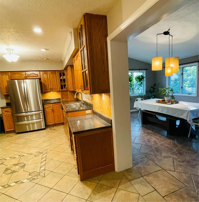 kitchen with lofted ceiling, sink, stainless steel refrigerator, and a healthy amount of sunlight