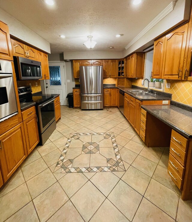 kitchen with crown molding, a textured ceiling, light tile patterned floors, stainless steel appliances, and sink