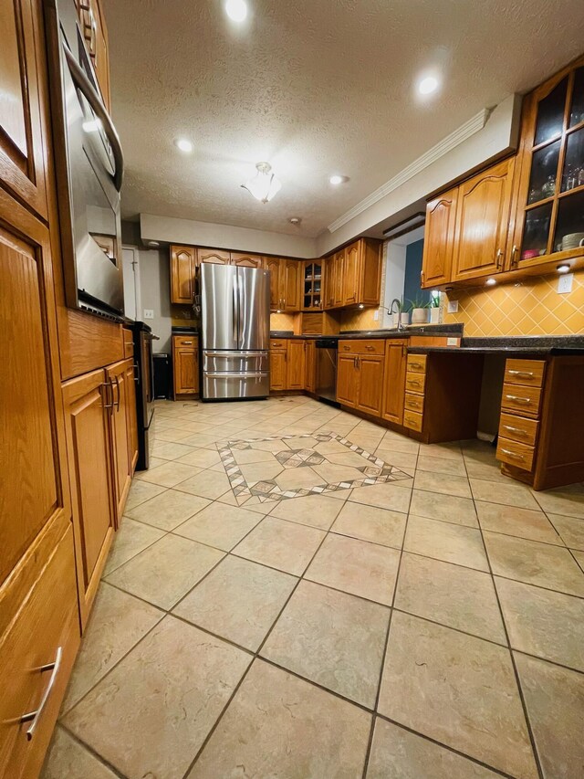 kitchen featuring crown molding, light tile patterned floors, a textured ceiling, and stainless steel appliances