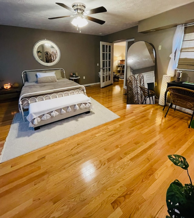 bedroom with ceiling fan, wood-type flooring, and a textured ceiling