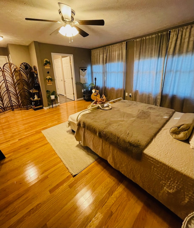 bedroom with a closet, ceiling fan, a textured ceiling, and light hardwood / wood-style flooring