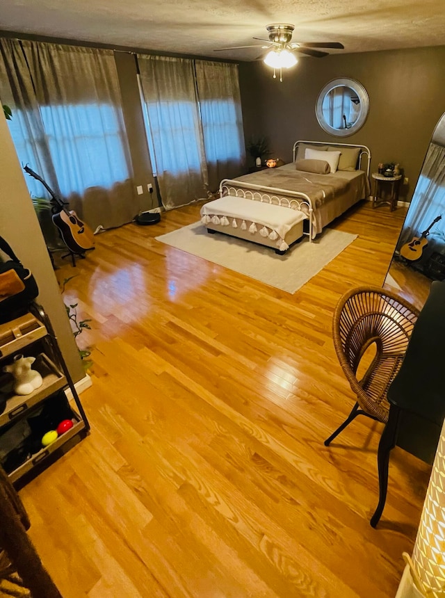 bedroom with a textured ceiling, ceiling fan, and light hardwood / wood-style floors