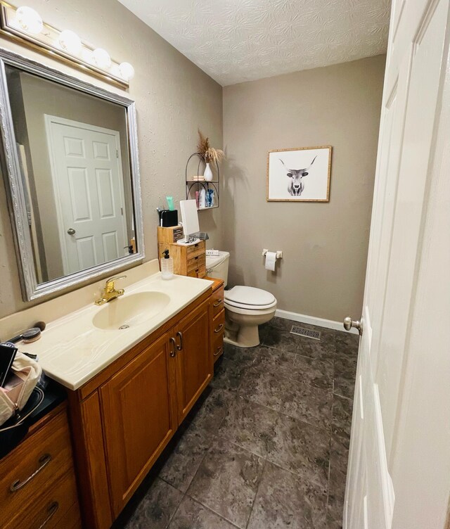 bathroom featuring a textured ceiling, vanity, and toilet