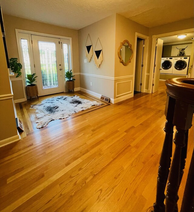 foyer with a textured ceiling, independent washer and dryer, and wood-type flooring