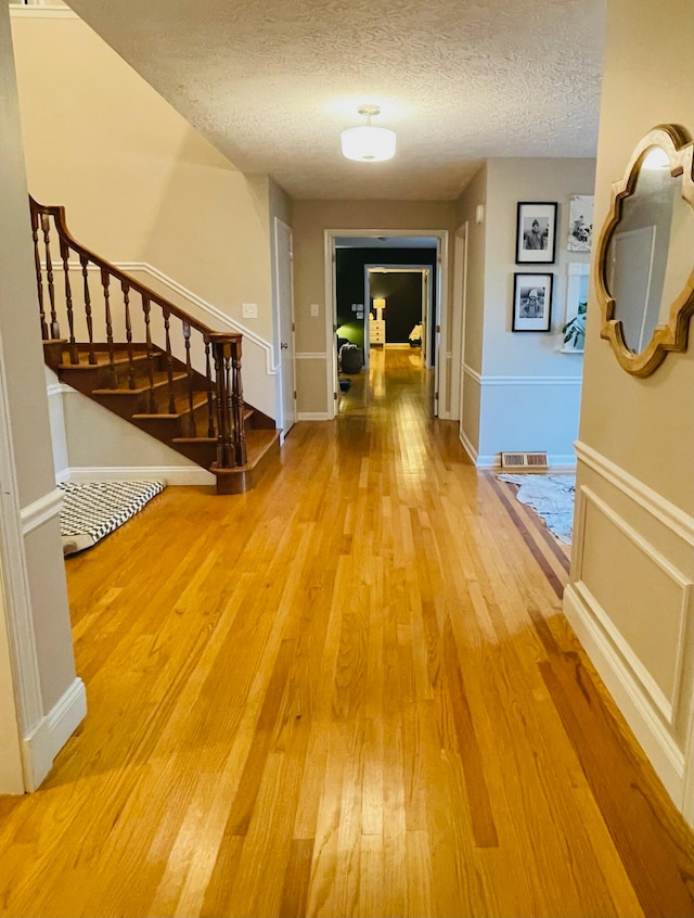 hall with hardwood / wood-style floors and a textured ceiling