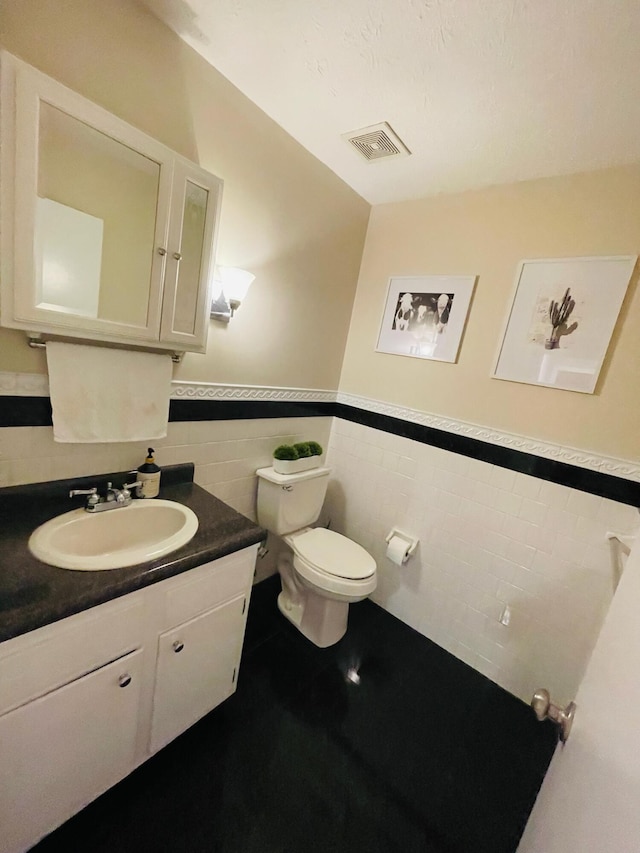 bathroom featuring vanity, toilet, backsplash, and tile walls