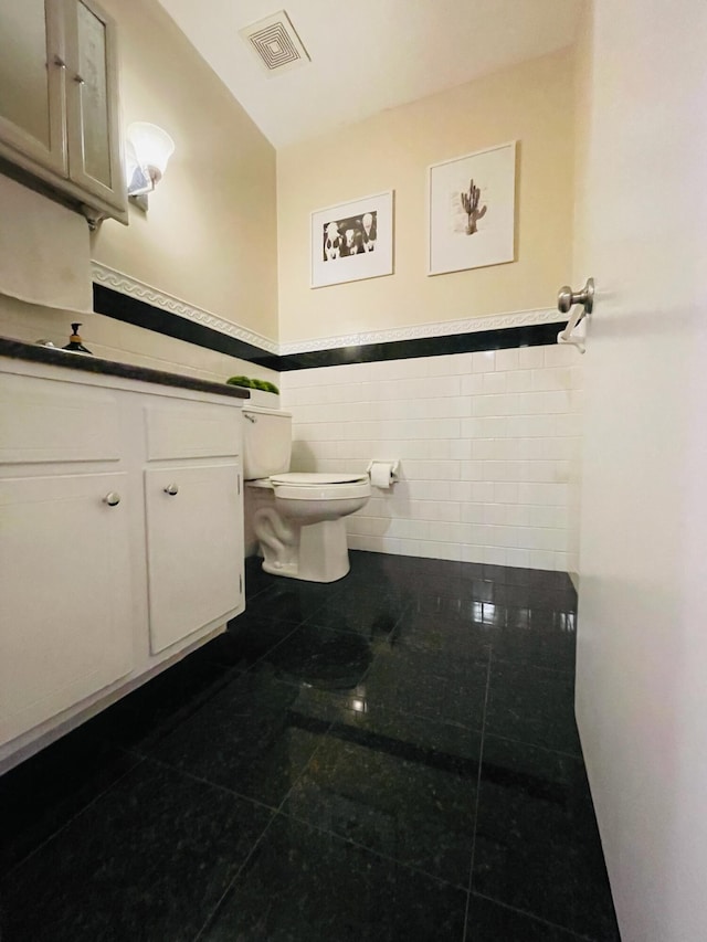 bathroom featuring tile patterned floors, tile walls, toilet, and vanity