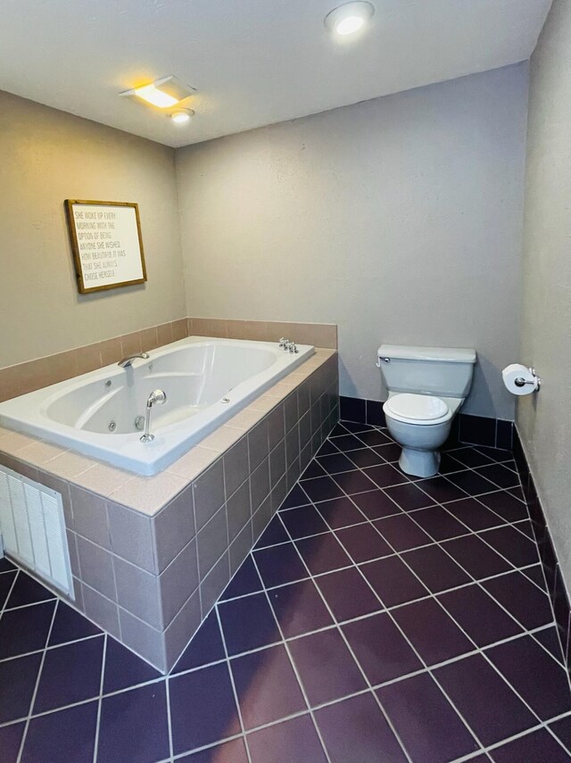 bathroom with tile patterned flooring, tiled tub, radiator heating unit, and toilet