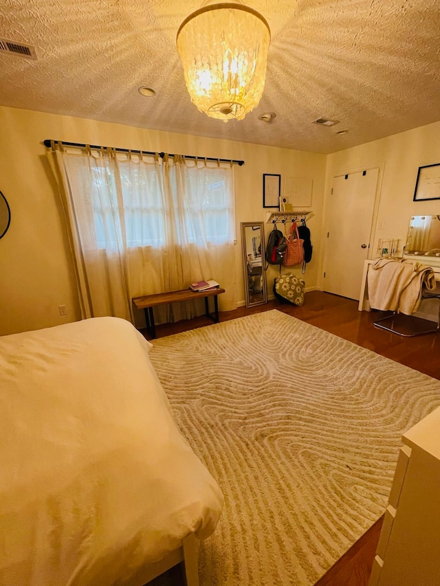 bedroom featuring dark hardwood / wood-style flooring, a notable chandelier, and a textured ceiling