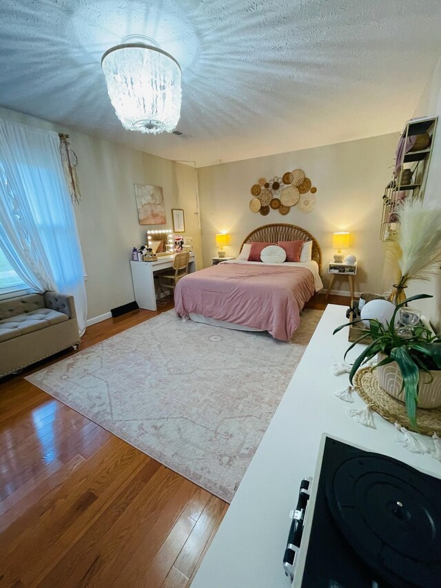 bedroom featuring a textured ceiling, hardwood / wood-style floors, and an inviting chandelier