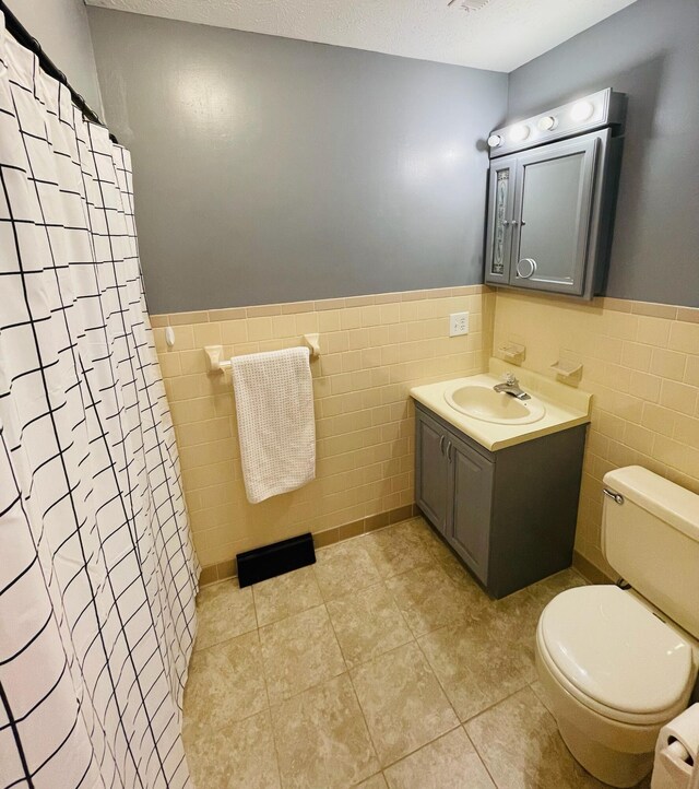 bathroom featuring a shower with shower curtain, vanity, toilet, and tile walls