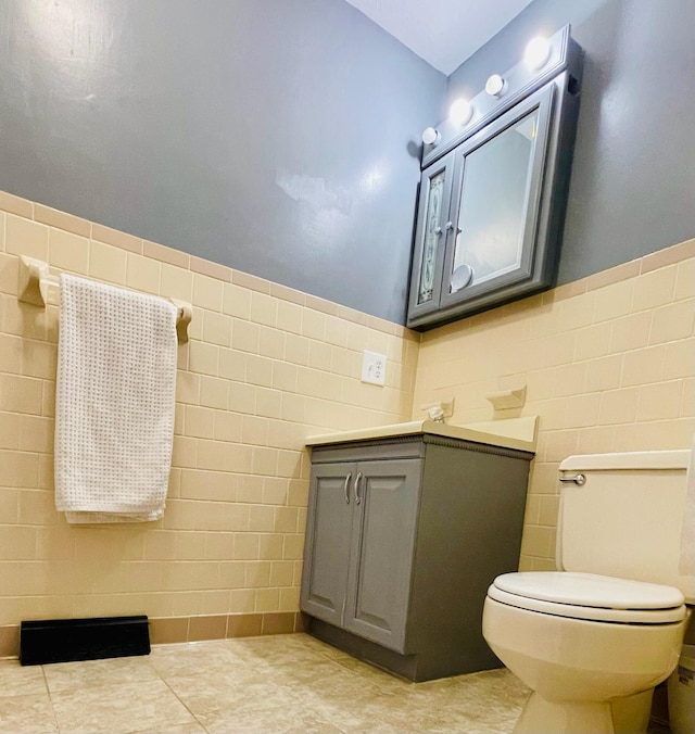 bathroom with tile walls, tile patterned flooring, toilet, and vanity