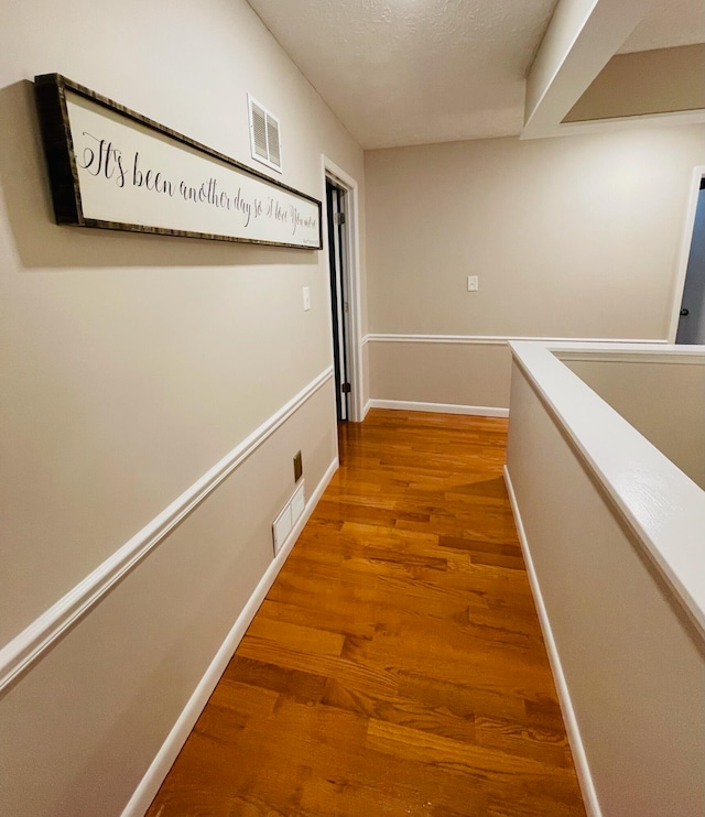 corridor featuring hardwood / wood-style floors and a textured ceiling