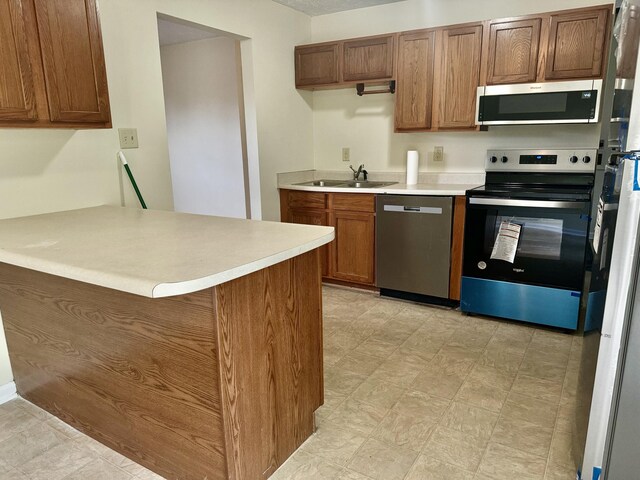 kitchen featuring kitchen peninsula, stainless steel appliances, and sink