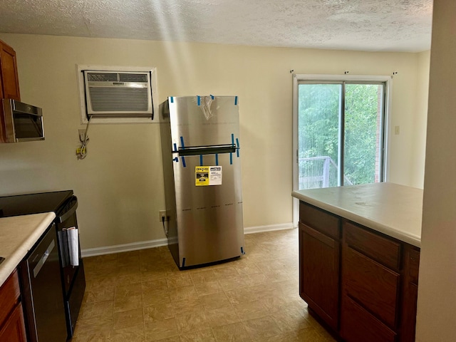 kitchen with a wall mounted AC, a textured ceiling, and stainless steel appliances