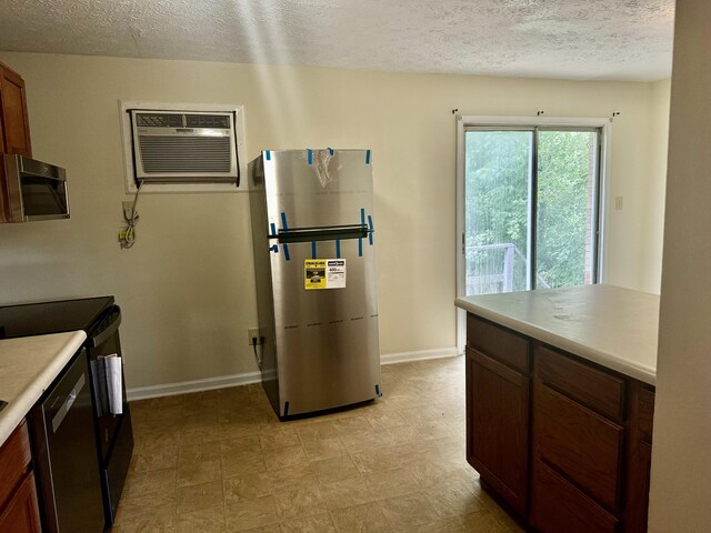 kitchen with a textured ceiling, a wall mounted AC, and stainless steel appliances