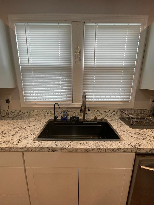 kitchen with white cabinetry, dishwasher, sink, and light stone counters