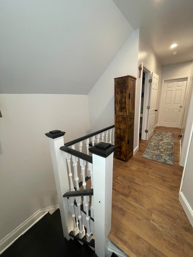 stairs featuring vaulted ceiling and hardwood / wood-style flooring