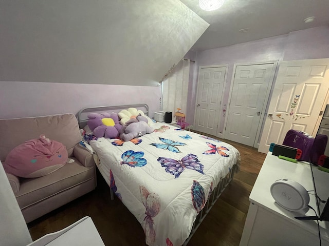 bedroom with vaulted ceiling, two closets, and dark hardwood / wood-style flooring