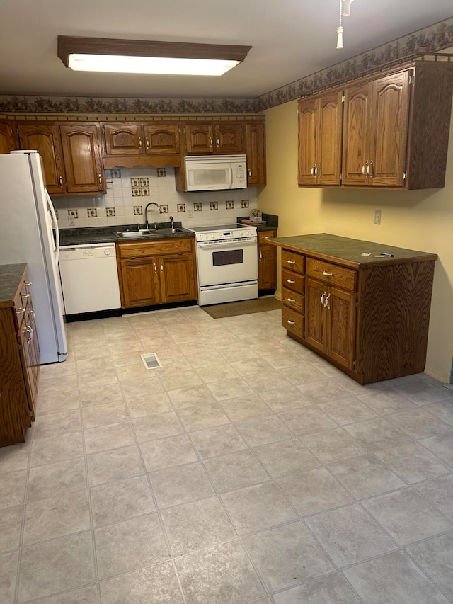 kitchen featuring white appliances, tasteful backsplash, and sink