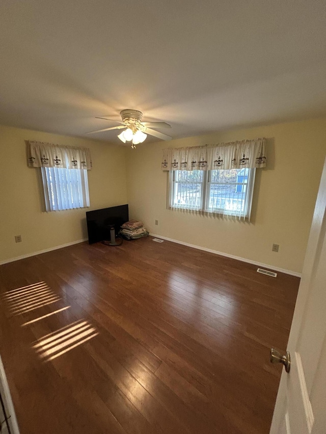 spare room with wood finished floors, a ceiling fan, and baseboards