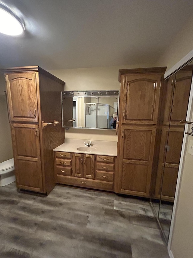 bathroom with wood finished floors, a stall shower, vanity, and toilet
