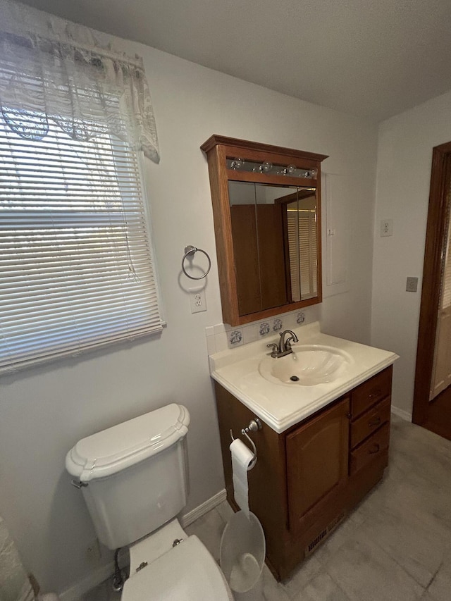 bathroom with toilet, vanity, and baseboards